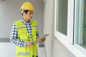 el inspector o ingeniero está inspeccionando la construcción y el aseguramiento de la calidad de la nueva casa usando una lista de verificación. ingenieros o arquitectos o contratistas trabajan para construir la casa antes de entregársela al propietario foto