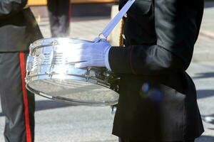 The silver drum in the hands of a military band musician sparkles in the sun. photo