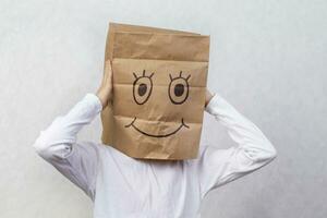 A child with cardboard boxes on his head, on which a smile is drawn with a marker. The concept of holiday shopping, moving. photo