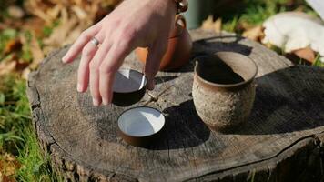 men's hands put bowls for a tea ceremony on a wooden stump. street tea concept. Chinese tea utensils video