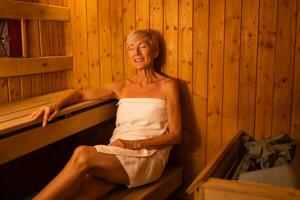 Mature woman is relaxing in sauna. Healthy lifestyle for elderly people. Spa concept. photo