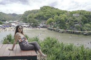 Young Asian girl sitting on the edge of cliff above the sea hearing wind by herself. Holiday concept photo