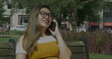 Young Woman Talks on Phone on a Park Bench video