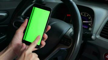 mão segurando Móvel telefone verde tela às carro, usando telefone às carro, Smartphone verde tela video