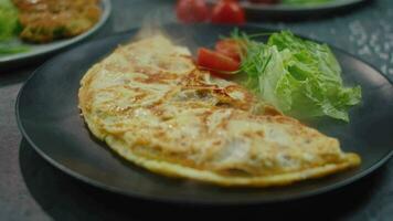 Omelett mit Grüner Salat und Tomate auf ein Teller im künstlich Rauch video