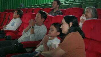 divers mensen in theater. Aziatisch familie en multiraciaal publiek zijn bang van aan het kijken thriller en verschrikking bioscoop, bang samen Aan film fase, en vermaak levensstijl met film kunst show. video