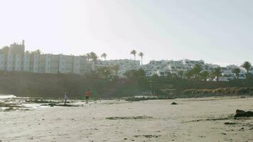 Garoto é uma pedra atirador. de praia cena com hotéis dentro Lanzarote video