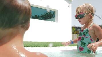 A girl playing in a pool with her family video