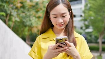 asiatisch Mädchen chatten und SMS während Gehen unter das Gebäude. video