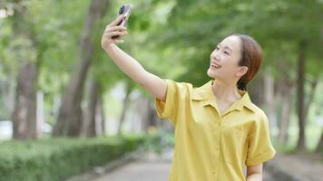 mulher segurando uma Smartphone levando uma selfie levando uma foto do dela braço relaxa em uma confortável dia video