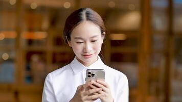 asiatique femme envoyer des SMS sur mobile en plein air video