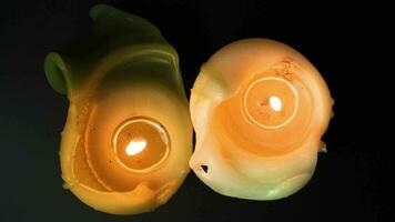 Igniting candles top view on black background. Candles burn and than light out on high framerate. Green and white natural wax candles close up. Sadness symbol video