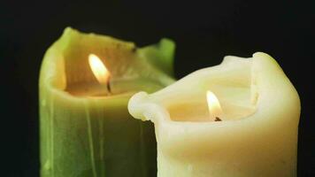 Igniting candles top view on black background. Candles burn and than light out on high framerate. Green and white natural wax candles close up. Sadness symbol video