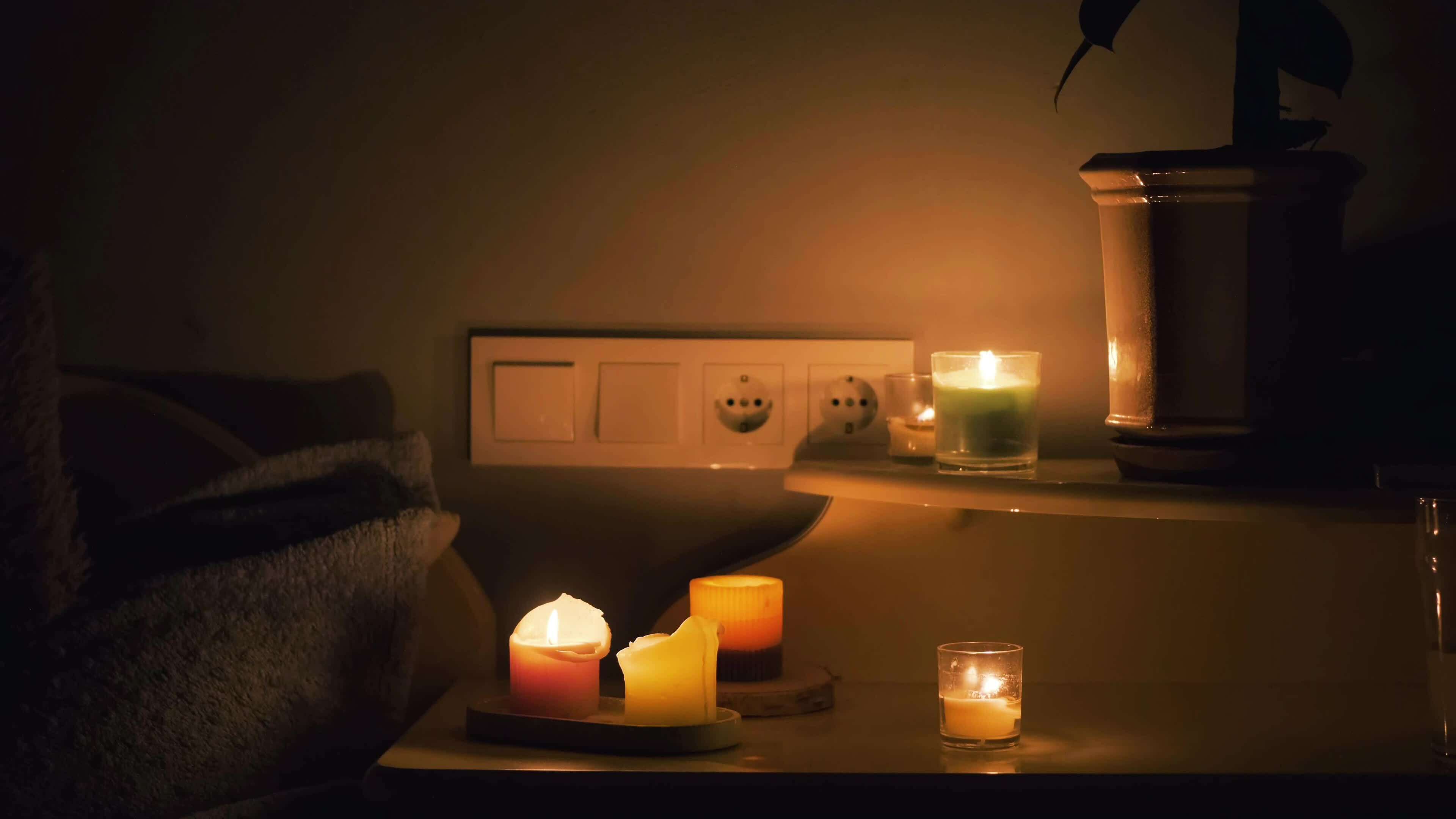 Candles in a dark room. Burning candles on the table and sockets on the  background. No electricity in the house. Blackout in the city. Power outage,  energy crisis concept 28623639 Stock Video
