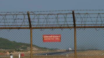 PHUKET, THAILAND JANUARY 22, 2023 - Boeing 767 3Y0ER, RA 73079 of Azur Air taking off at Phuket Airport. Airfield runway behind the fence. Foreground plate restricted area video