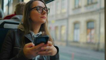 Publique transport. femme dans des lunettes dans tram en utilisant téléphone intelligent video
