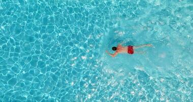 superiore giù Visualizza di un' uomo nel rosso pantaloncini nuotate nel il piscina. video