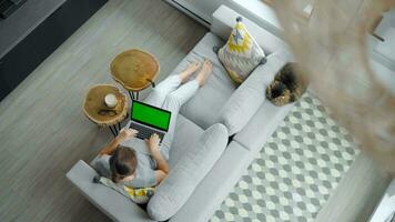 Overhead shot of woman uses laptop with green mock-up screen video