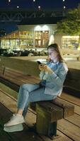 Vertical video. Woman uses smartphone at night. video