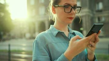 femme en utilisant téléphone intelligent tandis que permanent en plein air à le coucher du soleil video