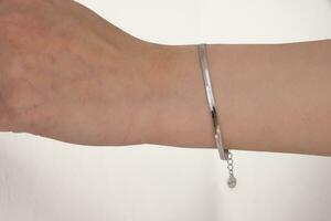 Woman wrist wearing silver snake chain bracelet set against a white background.  Beautiful valentine's gift. photo