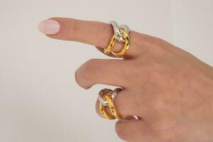 Woman hand wearing Interlocked Golden and Silver Rings set against a white background. Beautiful valentine's gift. photo