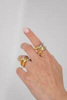 Woman hand wearing Interlocked Golden and Silver Rings set against a white background. Beautiful valentine's gift. photo