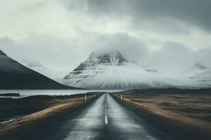 the road near the mountain with snow covering it on a cloudy day photo