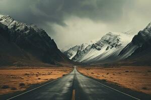 the road near the mountain with snow covering it on a cloudy day photo