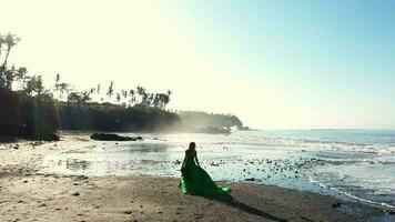 niña en un largo vestir corriendo en un negro playa en bali grande olas en el océano. video