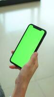 main en portant mobile téléphone avec vert écran à maison, en utilisant téléphone vert filtrer, vert filtrer, téléphone intelligent vert écran video