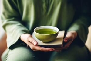 calma escena de manos de plataforma un verde té taza con un atención plena libro cerca ai generativo foto