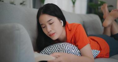 Asian woman reading a book while lying on the sofa photo