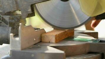 A man uses an electric circular saw to cut wooden bars. Carpenter works on a board outdoors, close-up video