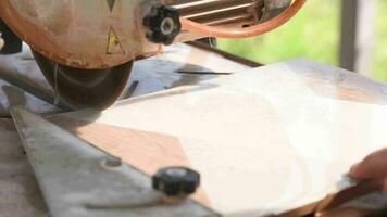 Close-up of a man cutting tiles and granite with an electric circular saw and applying water to it video