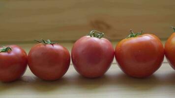 un' riga di rosso pomodori di diverso dimensioni e forme su un' di legno tavolo. video