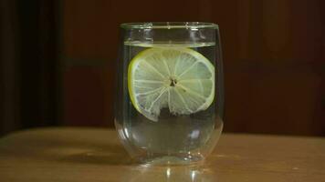 Clean drinking water with lemon floating in it in a transparent glass. video