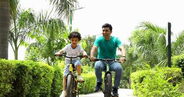 Stock video of father and son riding their bicycles in park