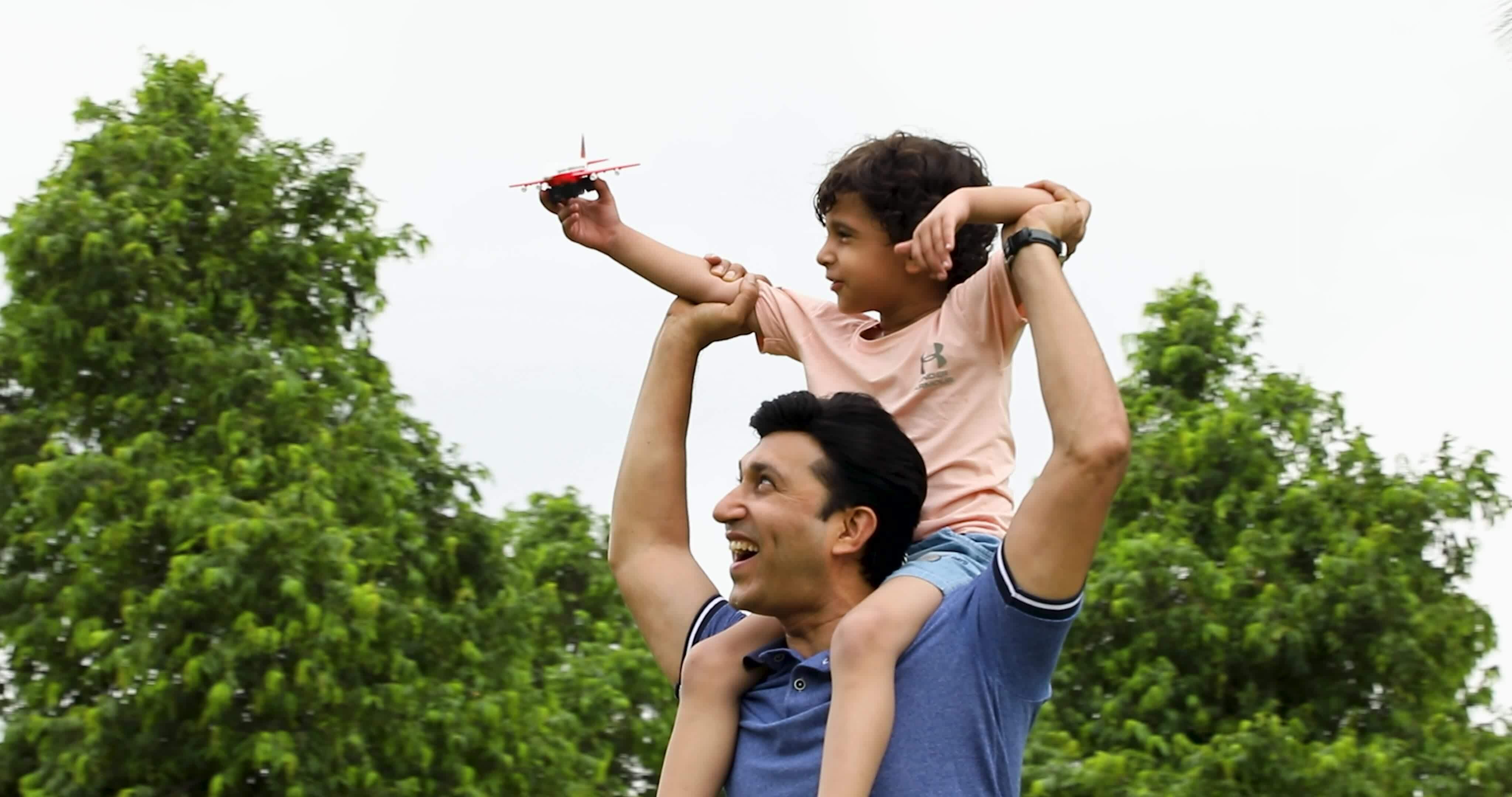 Senior father and his adult son with drone on a field - a Royalty