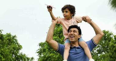 Video of happy father giving his son piggy back ride on his shoulders in park