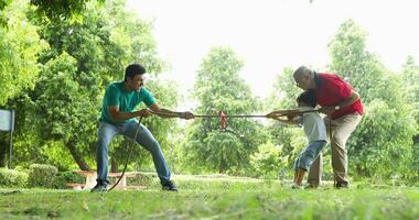 Video of grandson and grandfather competing with father in tug of war game