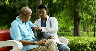 Video of Doctor putting on sling to relieve pain of patient while sitting on bench in park