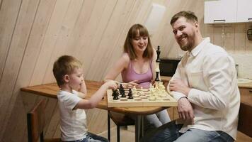 Lycklig familj mor, pappa och deras son spelar schack i de rum video