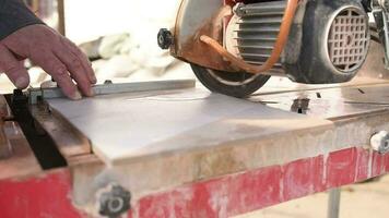 Close-up of a man cutting tiles and granite with an electric circular saw and applying water to it video