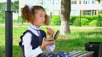 ragazza con zaino mangiare Sandwich confezionato nel un' Sandwich scatola vicino scuola. un' Presto merenda con un' panino, malsano cibo, pranzo a partire dal scuola. indietro per scuola. formazione scolastica, primario scuola classi, settembre 1 video