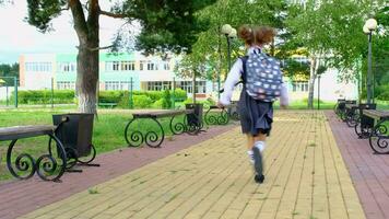 alegre engraçado menina com desdentado sorrir dentro escola uniforme com branco arcos corrida dentro escola quintal. costas para escola, setembro 1. feliz aluno com mochila. primário Educação, elementar aula. movimento video