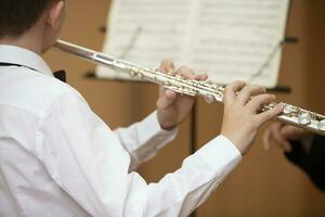 The boy plays the shining flute. Wind musical instrument. photo