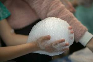 Laboratory chemistry experiment with foam and steaming.Laboratory chemical experiment with foam and steam. Hands holding foam. photo