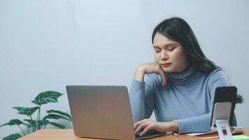 asiatique Jeune femelle avec cou douleur tandis que séance sur bureau travail vente en ligne. video