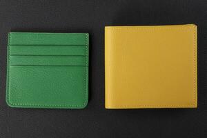 Leather products. Wallet business card holder made of green and yellow genuine leather on a black background. photo